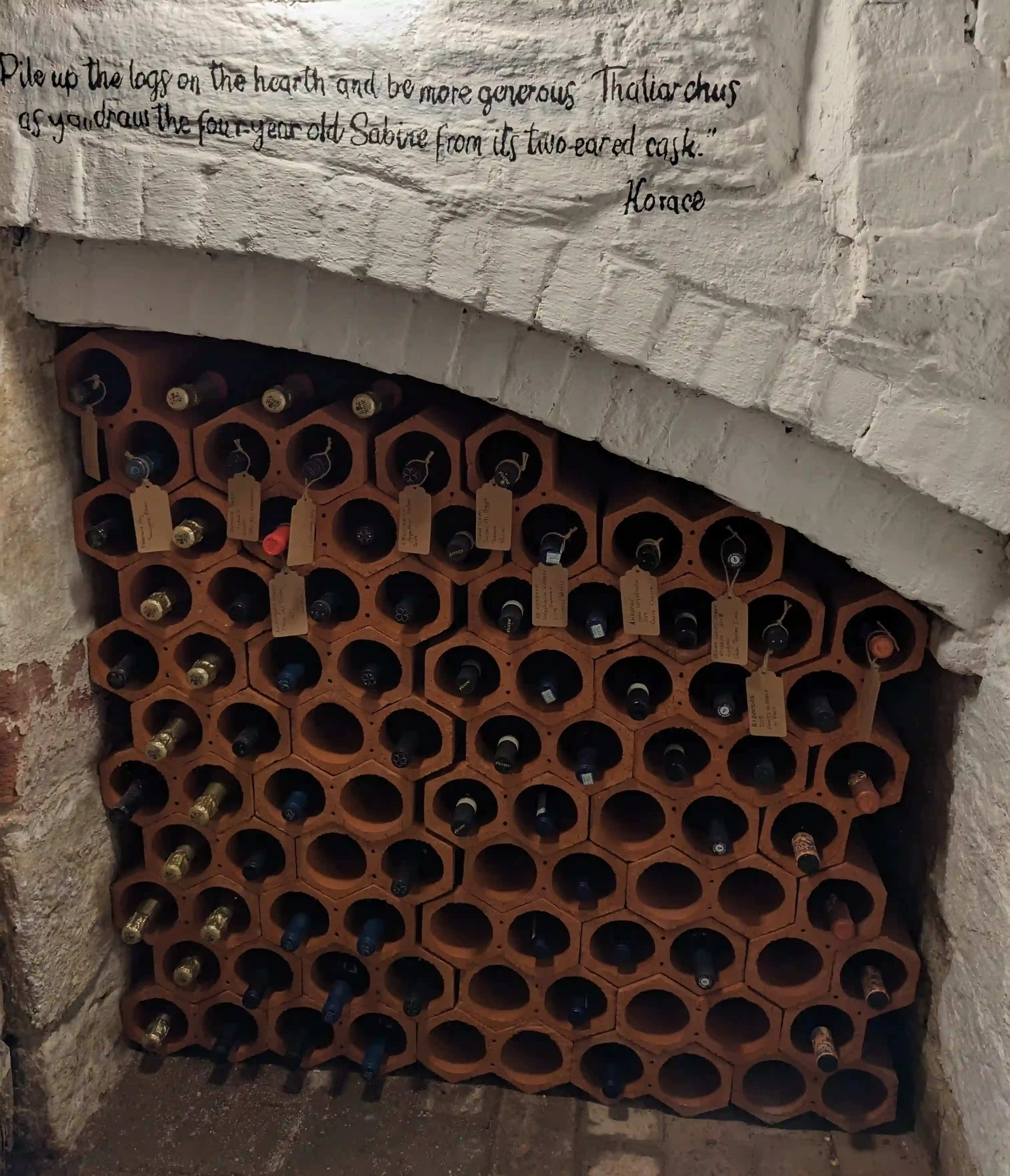 Terracotta wine rack in cellar with Horace quote
